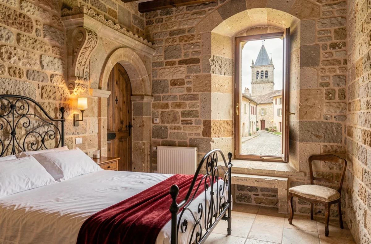 Chambre médiévale du Logis des Remparts à Saint-Émilion avec pierres en calcaire et vue sur le village classé UNESCO