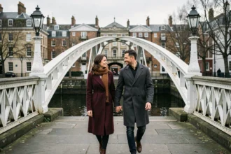 Couple romantique se promenant main dans la main sur le Ha'penny Bridge de Dublin en février, vêtements chauds d'hiver et reflets sur la Liffey